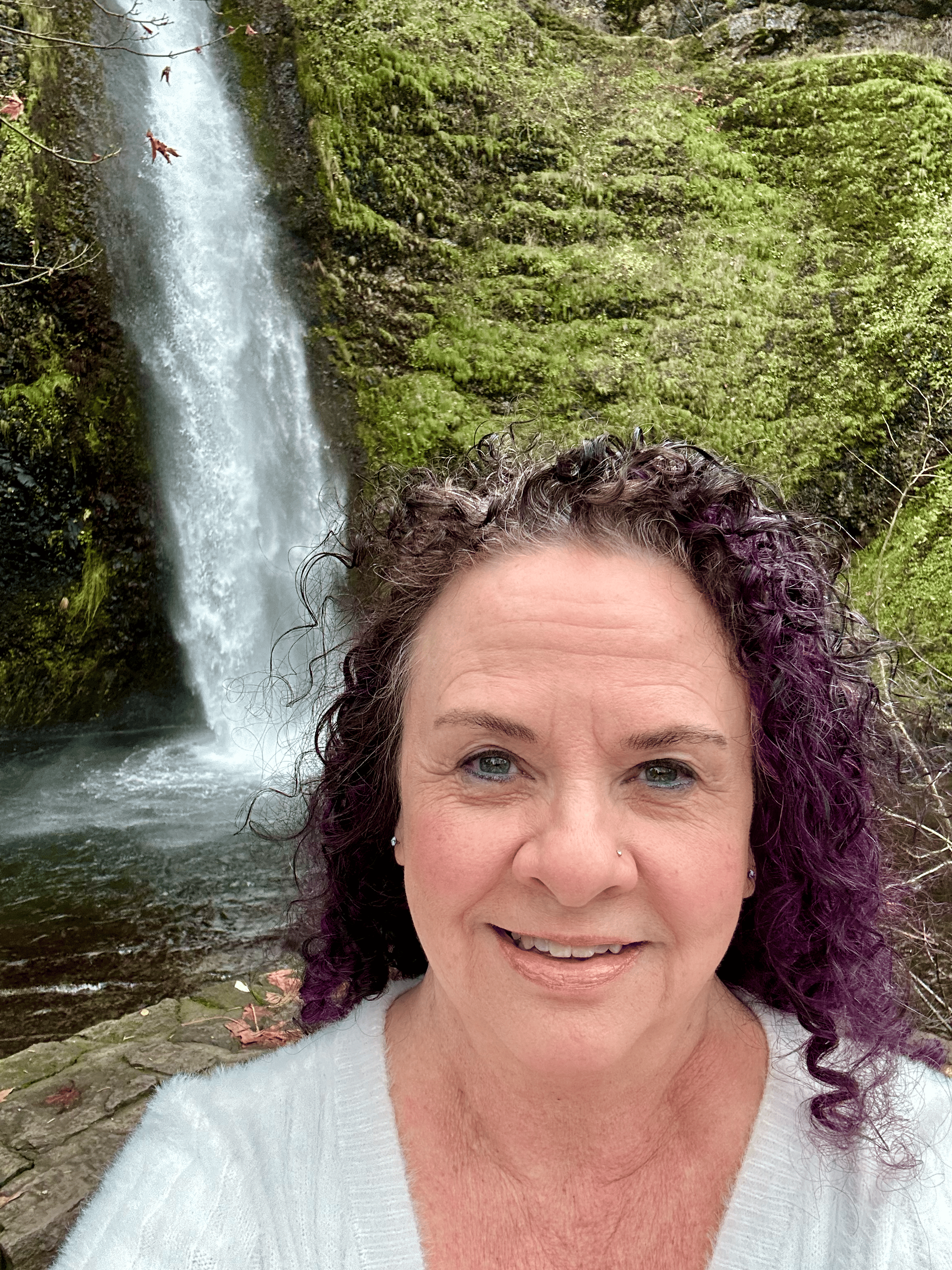 Pam Caldwell owner of Herb Lore standing by waterfall
